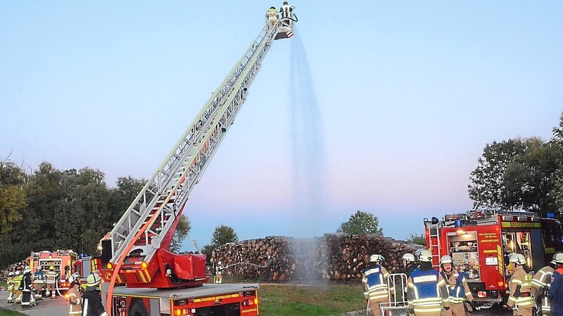 Dieser Holzstoß im Hintergrund war in Brand geraten und es galt für die drei Feuerwehren, größeren Schaden zu vermeiden.