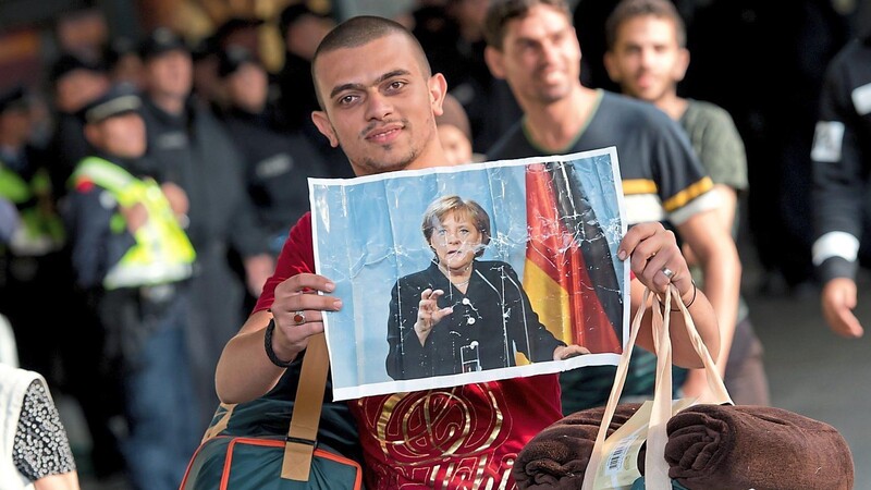 Ein Flüchtling hält am Münchner Hauptbahnhof ein Foto von Angela Merkel in den Händen.