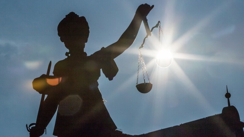 Die Morgensonne scheint hinter der Waagschale einer Justitia-Statue. Vor dem Landgericht Regensburg muss sich ein 27-Jähriger wegen Messerstichen verantworten.