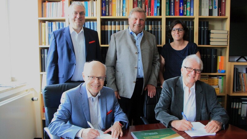 Franz Wittmann (vorne links) und Michael Heller (rechts) unterzeichnen unter den Augen von Johann Urban, Hans Weber und Maria Haimerl (hinten von links) den Partnerschaftsvertrag.