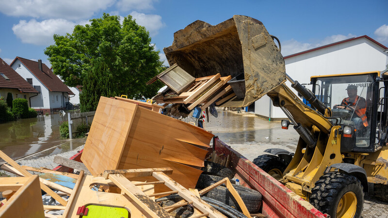 In einem Bauhof wird mit einem Radlader der durch Hochwasser entstandene Sperrmüll in einen Container gekippt. Die deutschen Versicherer fürchten hohe Schäden.