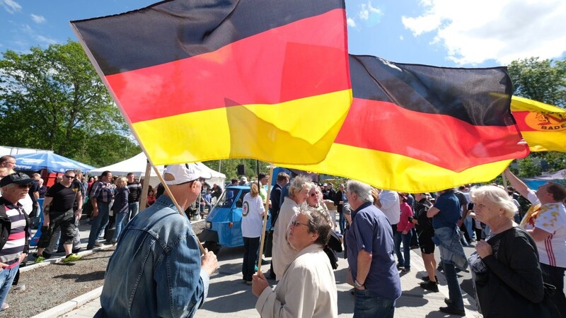 Teilnehmer einer Kundgebung der AfD versammeln sich in Zwickau und tragen Deutschlandfahnen.