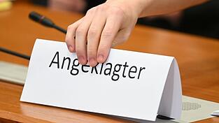 Ein Schild mit der Aufschrift 'Angeklagter' wird auf die Gerichtsbank gestellt. Ein Schild mit der Aufschrift 'Angeklagter' wird auf die Gerichtsbank gestellt.