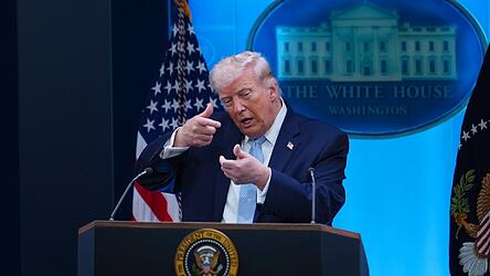 US-Präsident Donald Trump tut während einer Pressekonferenz so, als ziele er mit einem Scharfschützengewehr. (Symbolbild) US-Präsident Donald Trump tut während einer Pressekonferenz so, als ziele er mit einem Scharfschützengewehr. (Symbolbild)