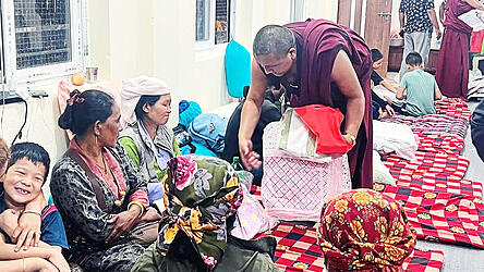 Ein Mönch aus dem Kloster Kopan in Kathmandu beim Austeilen von Care-Paketen an Frauen mit ihren Kindern, die sich vor der Sturzflut im Trishuli-Tal in Sicherheit bringen konnten. Ein Mönch aus dem Kloster Kopan in Kathmandu beim Austeilen von Care-Paketen an Frauen mit ihren Kindern, die sich vor der Sturzflut im Trishuli-Tal in Sicherheit bringen konnten.