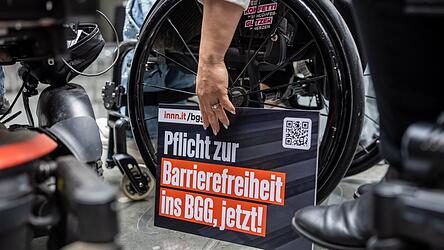 Ein Schild mit der Forderung „Pflicht zur Barrierefreiheit ins BBG, jetzt!“ steht bei der Übergabe einer Petition zur Reform des Behindertengleichstellungsgesetzes am Rad eines Rollstuhls. Ein Schild mit der Forderung „Pflicht zur Barrierefreiheit ins BBG, jetzt!“ steht bei der Übergabe einer Petition zur Reform des Behindertengleichstellungsgesetzes am Rad eines Rollstuhls.