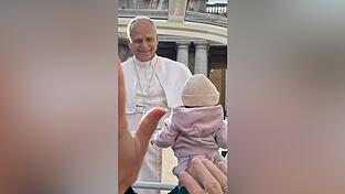 Direkt vor der Reisegruppe hält das Papamobil und Papst Leo XIV. segnet ein Kind. Direkt vor der Reisegruppe hält das Papamobil und Papst Leo XIV. segnet ein Kind.