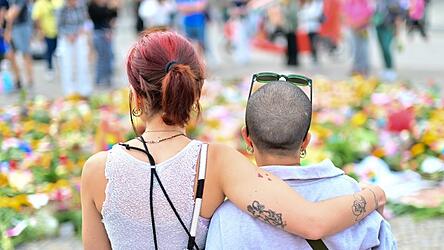 Menschen stehen an Beileidsbekundungen Blumen, Flaggen und Kerzen, die vor dem Brandenburger Tor abgelegt wurden. Menschen stehen an Beileidsbekundungen Blumen, Flaggen und Kerzen, die vor dem Brandenburger Tor abgelegt wurden.