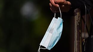 Ein Frau hält ihren Mund-Nasen-Schutz in der Hand. Ein Frau hält ihren Mund-Nasen-Schutz in der Hand.