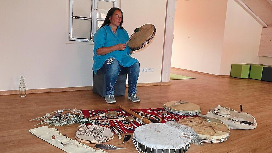 Bettina Lorenz, die sich als Schamanin White Wind Whisper nennt, bei einer Trommelreise; vor ihr weitere Trommeln, Flöten und andere Gegenstände aus ihrer Werkstatt. Bettina Lorenz, die sich als Schamanin White Wind Whisper nennt, bei einer Trommelreise; vor ihr weitere Trommeln, Flöten und andere Gegenstände aus ihrer Werkstatt.