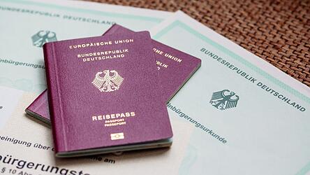 Zwei deutsche Reisepässe liegen auf Einbürgerungsurkunden der Bundesrepublik Deutschland sowie einem Einbürgerungstest. Zwei deutsche Reisepässe liegen auf Einbürgerungsurkunden der Bundesrepublik Deutschland sowie einem Einbürgerungstest.